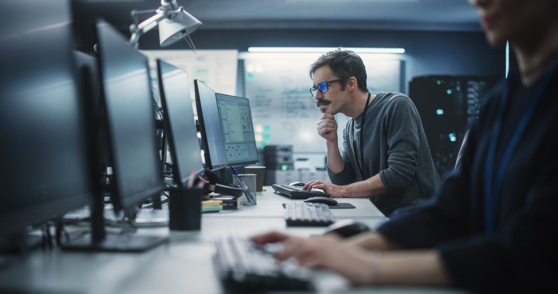 Portrait of a Thoughtful Engineer Working on Desktop Computer in a Technological Office Environment. Research and Development Department Writing Software Code for an Innovative Internet Project